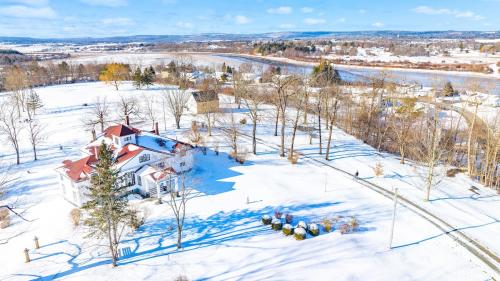 Alt text- Photo of Clifton Museum Park in winter on a sunny day with blue sky. In the foreground the lawn is covered in smooth white snow and long shadows from nearby bare trees. In the background the large, old, white house is covered in snow.