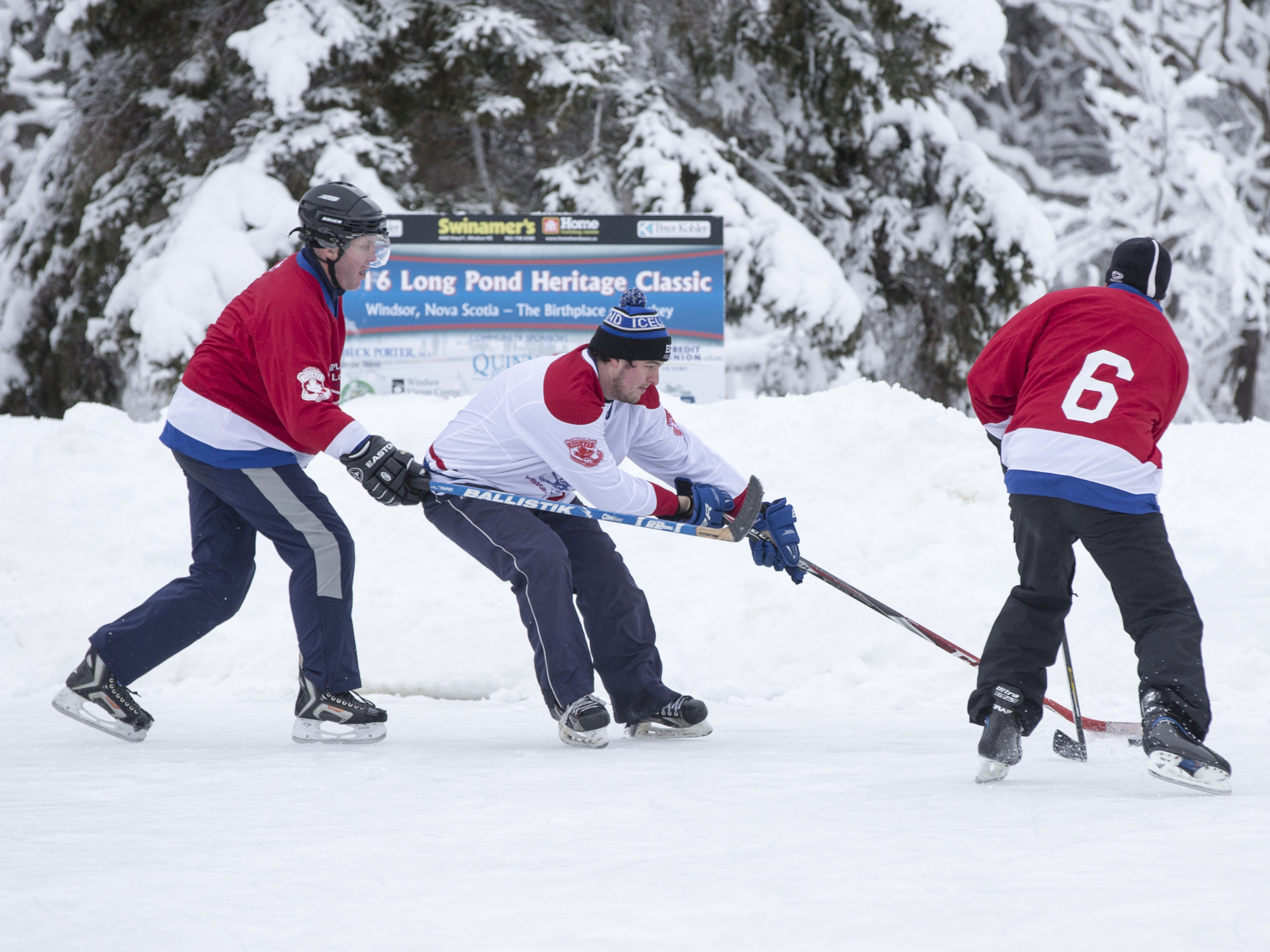 Three hockey players on the ice at Long Pond, Windsor, Nova Scotia.
