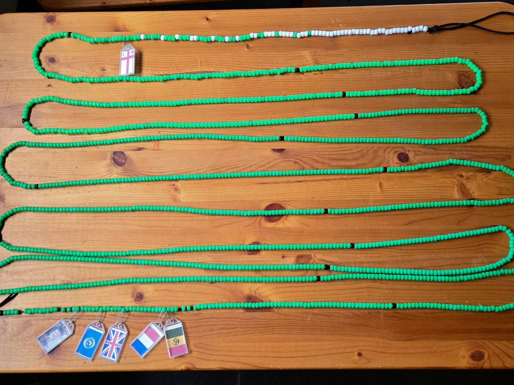 A wooded table with a long string of green beads.