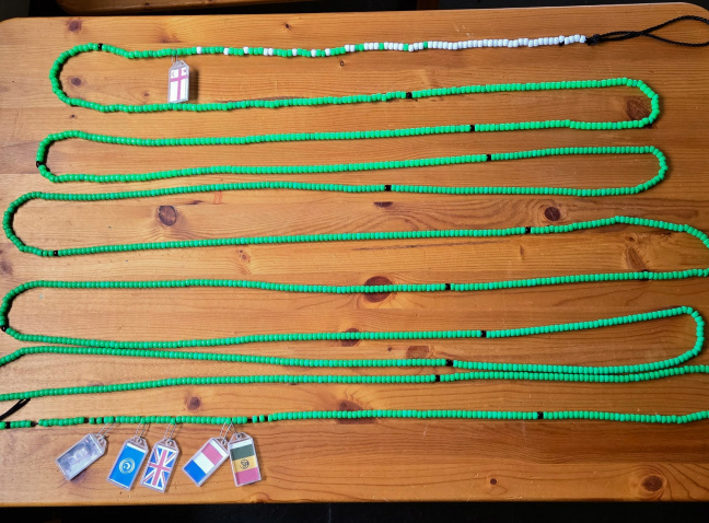 A wooded table with a long string of green beads.