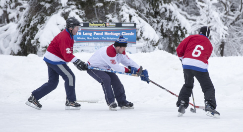 Three hockey players on the ice at Long Pond, Windsor, Nova Scotia.
